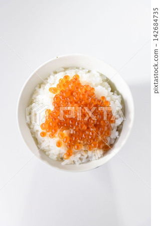 一碗令人垂涎的米飯,上面鋪滿了用醬油醃製過的色彩鮮豔的鮭魚籽。 一碗令人垂涎的米飯,上面鋪滿了用醬油醃製過的色彩鮮豔的鮭魚籽。 142684735
