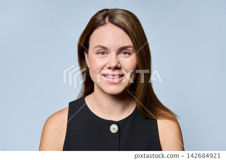 Close-up portrait of smiling young businesswoman looking at camera on gray background Close-up portrait of smiling young businesswoman looking at camera on gray background 142684921