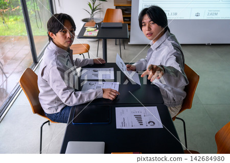 會議期間,兩名男子指著文件。 會議期間,兩名男子指著文件。 142684980
