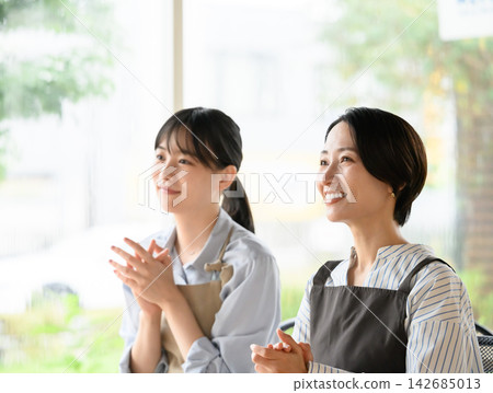 兩名女子麵帶微笑,鼓掌。 兩名女子麵帶微笑,鼓掌。 142685013