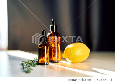 Essential oil amber glass bottles with lemon and rosemary Essential oil amber glass bottles with lemon and rosemary 142685081
