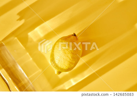 Lemon and glass water on yellow background with shadows 142685083