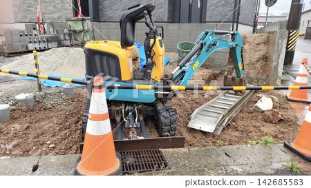 一台小型挖土機在住宅區和室外建築工地的狹窄空間內作業。 一台小型挖土機在住宅區和室外建築工地的狹窄空間內作業。 142685583