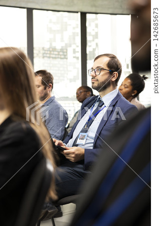 Male entrepreneur taking notes on laptop and sitting in conference room, listening to business presentation for development and training. Participant at international meeting event. Male entrepreneur taking notes on laptop and sitting in conference room, listening to business presentation for development and training. Participant at international meeting event. 142685673