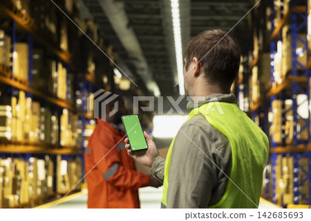 Vertical mockup on phone screen with personnel working on cargo dispatch, ensuring import export preparation. Professional environment highlighting operational logistics workflow. Vertical mockup on phone screen with personnel working on cargo dispatch, ensuring import export preparation. Professional environment highlighting operational logistics workflow. 142685693