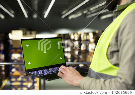 Green screen laptop with warehouse staff handling packages, contributing to logistics and distribution operations. Manual labor supporting shipping management and inventory control, supply chain. Green screen laptop with warehouse staff handling packages, contributing to logistics and distribution operations. Manual labor supporting shipping management and inventory control, supply chain. 142685699
