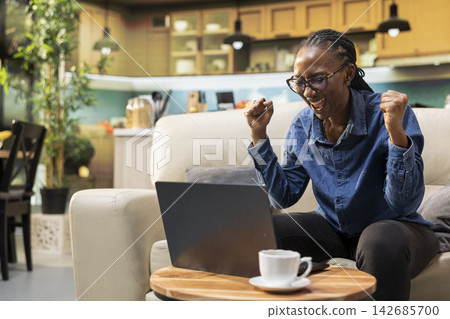 Pleased excited young adult being overjoyed after receiving promotion, uplifting good news for ambitious confident employee at home. Happy female with satisfaction and gratitude, excitement. 142685700