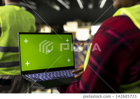 Isolated mockup screen, logistics staff member, laptop in warehouse, monitoring inventory and shipping workflow. Organized facility highlighting supply chain control, parcel tracking. Isolated mockup screen, logistics staff member, laptop in warehouse, monitoring inventory and shipping workflow. Organized facility highlighting supply chain control, parcel tracking. 142685723