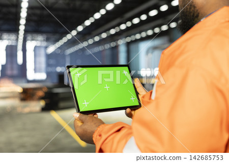 Mockup display tablet with black supervisor surrounded by metal tools in industrial facility, representing heavy industry labor and manufacturing power. Engineering workforce in factory. Mockup display tablet with black supervisor surrounded by metal tools in industrial facility, representing heavy industry labor and manufacturing power. Engineering workforce in factory. 142685753