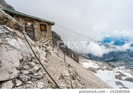 Alpine Mountain Hut on Rocky Slope with Cloudy Valley View Alpine Mountain Hut on Rocky Slope with Cloudy Valley View 142686066