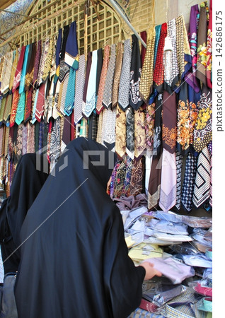 Iran, Isfahan, bazaar, necktie shop, woman wearing a chador. 142686175