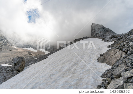 Snowy Alpine Mountain Landscape with Rocky Peaks and Clouds Snowy Alpine Mountain Landscape with Rocky Peaks and Clouds 142686292