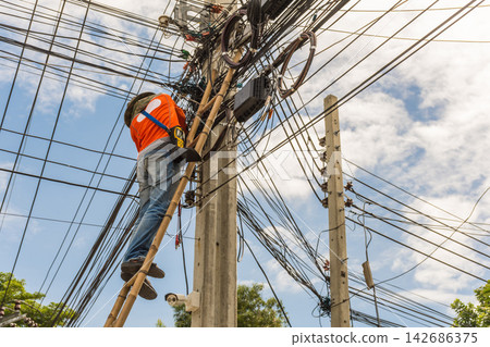 Utility Worker Repairing Overhead Power Lines on Ladder Utility Worker Repairing Overhead Power Lines on Ladder 142686375