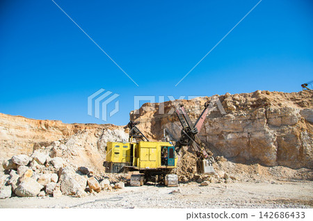 Mining Excavator in Open Pit Quarry Under Blue Sky Mining Excavator in Open Pit Quarry Under Blue Sky 142686433
