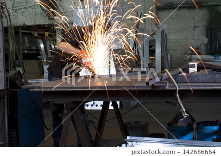 Industrial Welder Grinding Metal with Sparks in Workshop Industrial Welder Grinding Metal with Sparks in Workshop 142686664