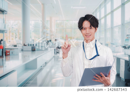 A male researcher wearing a white lab coat conducts research in a laboratory. A male researcher wearing a white lab coat conducts research in a laboratory. 142687343