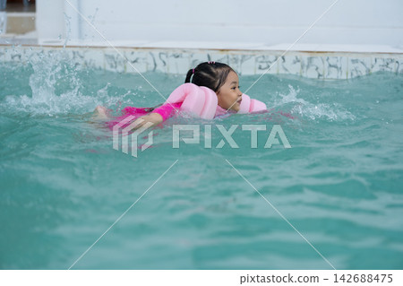 preschool child girl playing and swimming with floaties in pool water preschool child girl playing and swimming with floaties in pool water 142688475