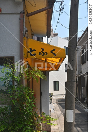 The retro yellow awning of "Shichifuku" stands in a back alley of the old town. The retro yellow awning of "Shichifuku" stands in a back alley of the old town. 142689307