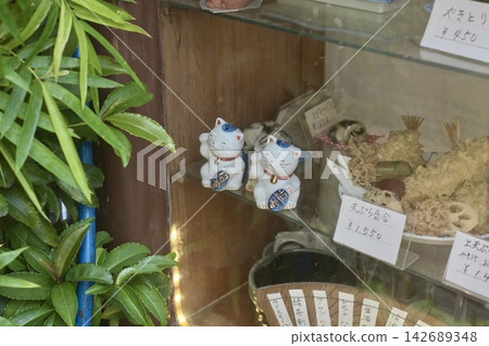 A lucky cat and handwritten menu displayed in the showcase of a long-established restaurant. A lucky cat and handwritten menu displayed in the showcase of a long-established restaurant. 142689348