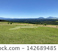 A vast mountain range and blue sky viewed from a sunny plateau. 142689485