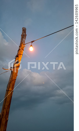 Rustic Wooden Pole with Hanging Light at Beach Dusk Rustic Wooden Pole with Hanging Light at Beach Dusk 142689965