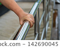 Close-up of Senior Woman's Hands Holding a Stainless Steel Handrail or Handrail for Safety on Walk Way. 142690045
