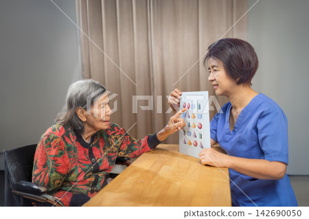 Asian Senior Woman with Dementia Doing Shape Matching Exercise with a Caregiver in Nursing Home. Asian Senior Woman with Dementia Doing Shape Matching Exercise with a Caregiver in Nursing Home. 142690050