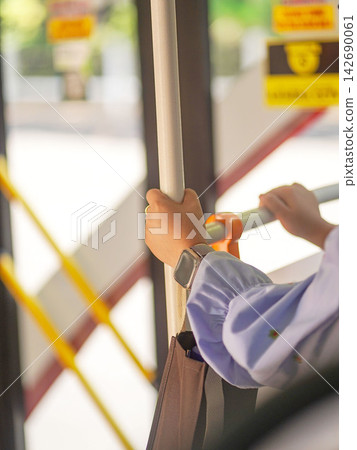 Close-up of a passenger's hand holding a handrail handle inside a public transport bus or train for balance during a daily city commute. 142690061