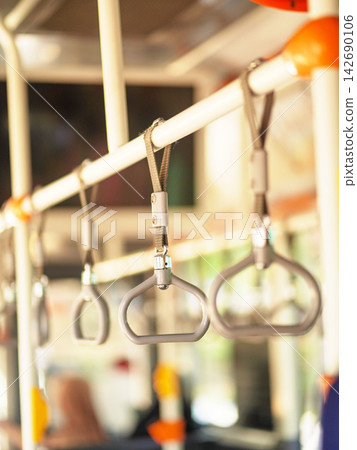 Row of hanging overhead handrail handles and grab straps inside a public transportation bus or train for passenger balance and safety. Row of hanging overhead handrail handles and grab straps inside a public transportation bus or train for passenger balance and safety. 142690106