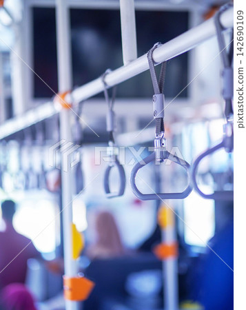 Row of hanging overhead handrail handles and grab straps inside a public transportation bus or train for passenger balance and safety. Row of hanging overhead handrail handles and grab straps inside a public transportation bus or train for passenger balance and safety. 142690109