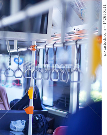 Row of hanging overhead handrail handles and grab straps inside a public transportation bus or train for passenger balance and safety. 142690111