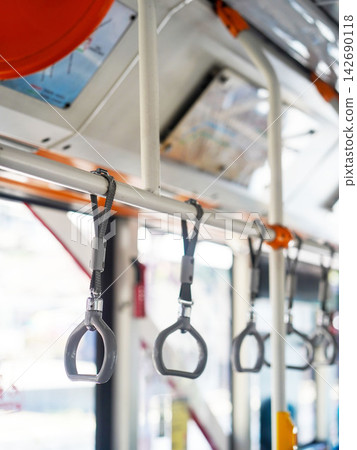 Row of hanging overhead handrail handles and grab straps inside a public transportation bus or train for passenger balance and safety. Row of hanging overhead handrail handles and grab straps inside a public transportation bus or train for passenger balance and safety. 142690118