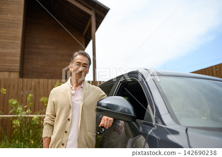 A smiling man standing next to a car, in front of his home. A smiling man standing next to a car, in front of his home. 142690238
