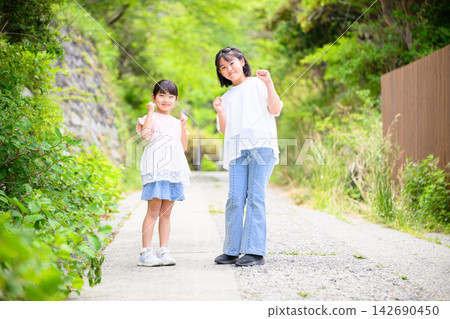 姐妹倆並肩站著,面帶微笑地擺著姿勢。 姐妹倆並肩站著,面帶微笑地擺著姿勢。 142690450