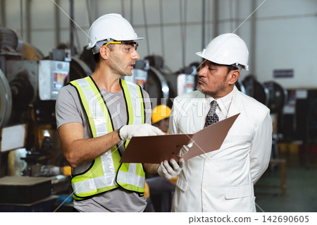 Asian factory manager discussing report with engineer in plant Asian factory manager discussing report with engineer in plant 142690605