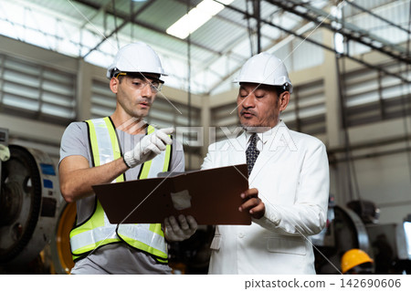 Asian factory manager discussing report with engineer in plant 142690606