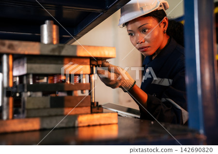 Female technician looking for metal component on industrial shelf 142690820