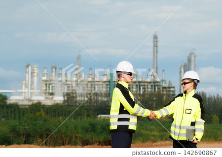 Male and female engineers shaking hands at refinery plant site Male and female engineers shaking hands at refinery plant site 142690867
