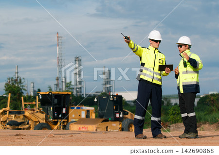 Engineers holding tablet discussing construction near refinery plant Engineers holding tablet discussing construction near refinery plant 142690868