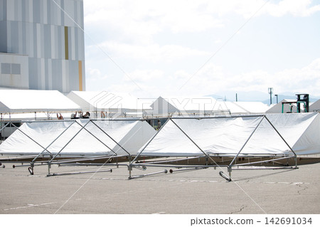 A scene of rows of white tents: images of setup and preparation. A scene of rows of white tents: images of setup and preparation. 142691034