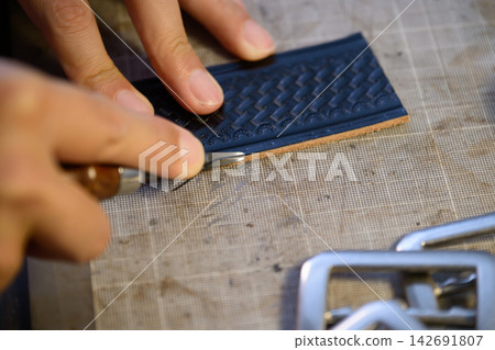 工匠正在處理皮帶的邊緣。 工匠正在處理皮帶的邊緣。 142691807