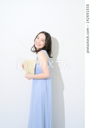 一位日本女性手持帽子,在白色背景前,展現出美麗的形象。 一位日本女性手持帽子,在白色背景前,展現出美麗的形象。 142691838