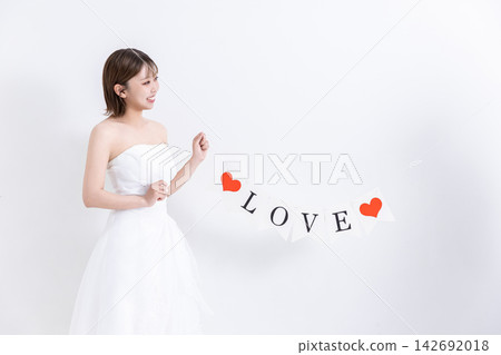 身穿婚紗的女孩手持心型飾品。 身穿婚紗的女孩手持心型飾品。 142692018