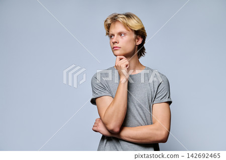 Portrait of thoughtful teenage boy looking away with hand on chin Portrait of thoughtful teenage boy looking away with hand on chin 142692465