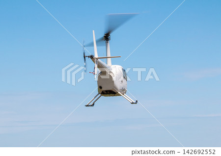 Back view of the small white helicopter flying in the sky Back view of the small white helicopter flying in the sky 142692552