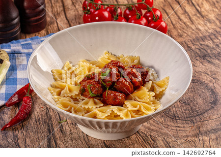 Farfalle pasta with meatballs and tomato sauce on a rustic wooden table 142692764