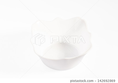White ceramic bowl with scalloped edge on clean white background, minimalist tableware design with soft shadows and glossy finish White ceramic bowl with scalloped edge on clean white background, minimalist tableware design with soft shadows and glossy finish 142692869