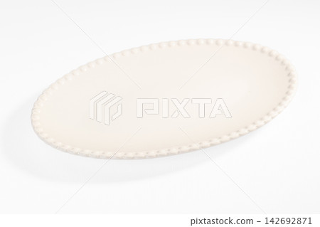 Oval white ceramic platter with beaded edge on clean white background, minimalist tableware design for food presentation Oval white ceramic platter with beaded edge on clean white background, minimalist tableware design for food presentation 142692871