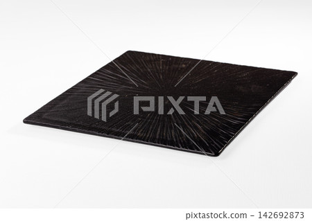 Black square plate with radial texture on white background, minimalist design, shallow depth of field, studio lighting Black square plate with radial texture on white background, minimalist design, shallow depth of field, studio lighting 142692873
