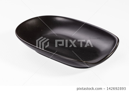 Black oval ceramic dish with smooth glossy finish on white background, minimalist design, shallow depth, soft shadow, studio lighting 142692893